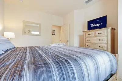 a bedroom with a large bed and a dresser at Family Spacious 3BR Townhouse with BBQ n' Pool Access in Kissimmee