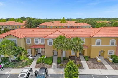 a large yellow house with palm trees in a parking lot at 3 Bed 2,5 Bath Perfect Family home Bunk Beds townhouse in Kissimmee