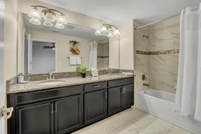 a bathroom with a tub and a sink and a tub and a mirror at 3097Pequod townhouse in Kissimmee