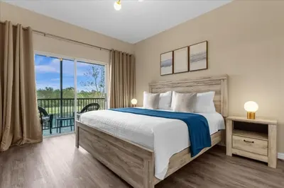a bedroom with a large bed and a balcony at Oakwater Retreat condo in Orlando