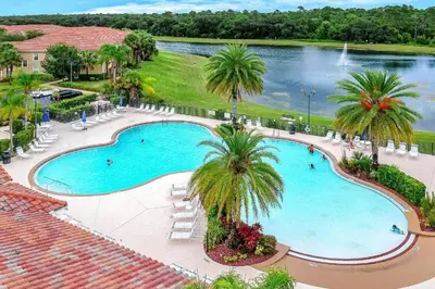 an overhead view of a pool with palm trees and a lake at Oakwater Retreat condo in Orlando