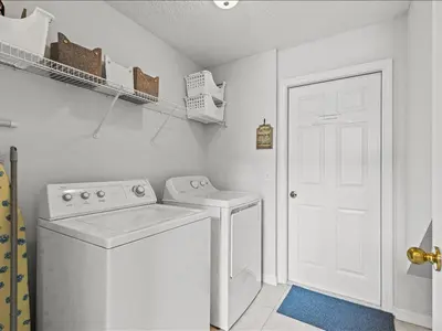 a white laundry room with a washing machine and a door at Treasure Hunt Retreat home in Kissimmee