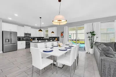a kitchen and living room with a white table and chairs at Storey Lake 6 bed Home- King Master on 1st Floor villa in Kissimmee