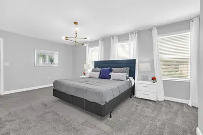 a white bedroom with a large bed and windows at Storey Lake 6 bed Home- King Master on 1st Floor villa in Kissimmee