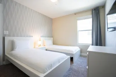 a white bedroom with two beds and a window at Storey Lake Pool Home with Resort Amenities near DISNEY in Kissimmee