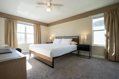 a bedroom with a large white bed and two windows at Storey Lake Pool Home with Resort Amenities near DISNEY in Kissimmee