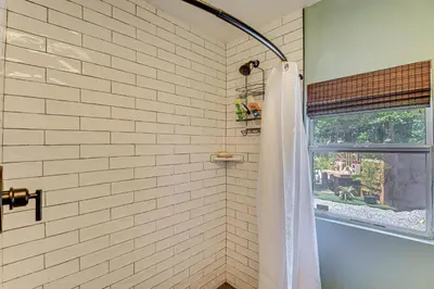 a white tiled shower with a window in a bathroom at Walk to Historic Dtwn Sanford Home with Gas Grill! in Sanford
