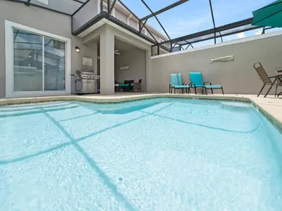 a large swimming pool with blue chairs and tables at 4978 Luxurious 4BR Sunshine Getaway at Storey Lake in Kissimmee
