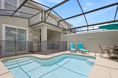 a house with a swimming pool with a table and chairs at 4978 Luxurious 4BR Sunshine Getaway at Storey Lake in Kissimmee