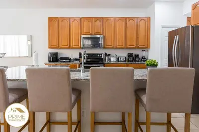 a kitchen with wooden cabinets and a counter with chairs at Amazing 6bd Resort Home Pool & Near Disney in Kissimmee