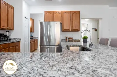 a kitchen with a granite counter top and a refrigerator at Amazing 6bd Resort Home Pool & Near Disney in Kissimmee