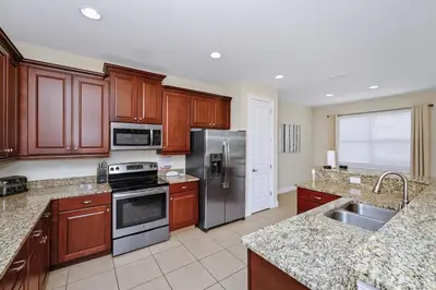 a kitchen with wooden cabinets and stainless steel appliances at Spacious Home Near Disney With Game And Themed Rooms With Waterpark & Resort Access At Encore Resorts Reunion - 581La in Kissimmee