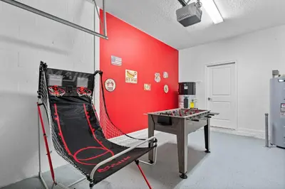 a room with a ping pong table and a red wall at 5 Bedroom 5 Bathroom Storey Lake 4760KC in Kissimmee