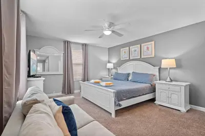 a bedroom with a white bed and a couch at 5 Bedroom 5 Bathroom Storey Lake 4760KC in Kissimmee