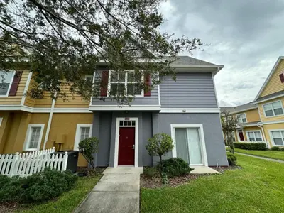 a house with a red door in a yard at 4 Bedroom 3 Bathroom Villas At Seven Dwarfs 8-107 in Kissimmee