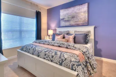 a bedroom with a large bed with purple walls at 4 Bedroom 3 Bathroom Storey Lake 4895CT in Kissimmee