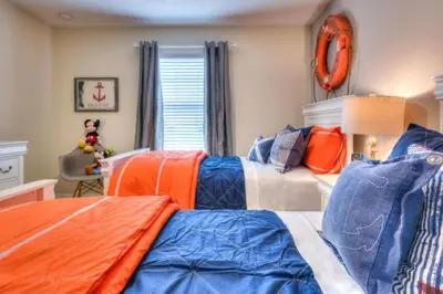 a bedroom with two beds with orange and blue at 4 Bedroom 3 Bathroom Storey Lake 4895CT in Kissimmee