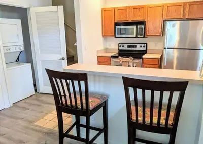 a kitchen with two chairs and a stove and refrigerator at 4 Bedroom 3 Bathroom Villas At Seven Dwarfs 8-108 in Kissimmee
