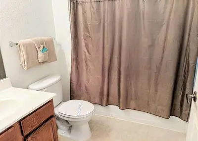 a bathroom with a toilet and a shower curtain at 4 Bedroom 3 Bathroom Villas At Seven Dwarfs 8-108 in Kissimmee