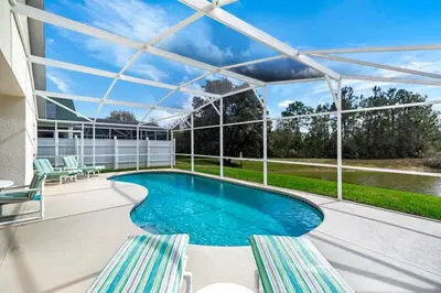 a swimming pool with two chairs and a pergola at 4 Bedroom Value Plus Home with Private PooI in Orlando