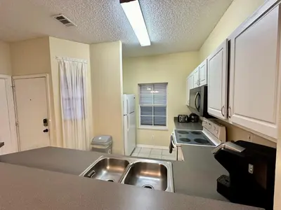 a kitchen with a stainless steel sink and a stove at Grand Emerald 3BR Condo Resort near Disney Parks in Kissimmee