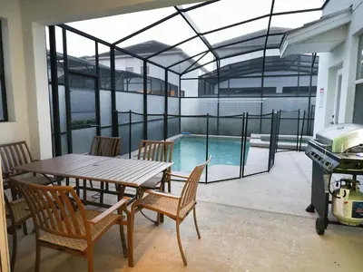 a patio with a table and chairs and a swimming pool at Themed 5BD Home Movie and Game Room 4726 in Kissimmee