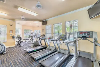 a fitness room with treadmills and elliptical machines at Magical Getaway Close to Disney! Pool, Gym, & WiFi in Kissimmee