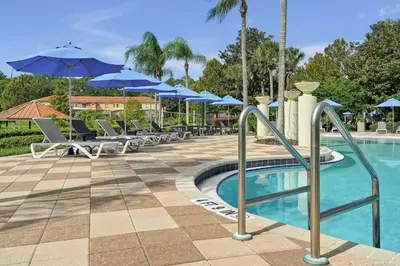 a pool with chairs and umbrellas at a resort at Stay Close to Disney in Your 3-Bedroom Haven in Kissimmee