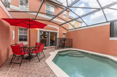 a patio with a table and chairs and a pool at Stay Close to Disney in Your 3-Bedroom Haven in Kissimmee