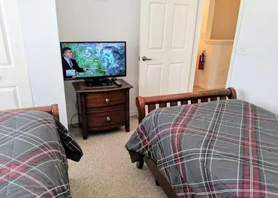 a bedroom with two beds and a flat screen tv at 4 Bedroom 3 Bathroom Villas At Seven Dwarfs 17-107 in Kissimmee