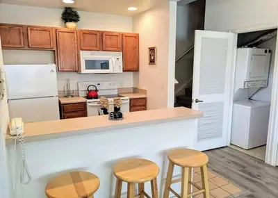 a kitchen with a counter and two stools at 4 Bedroom 3 Bathroom Villas At Seven Dwarfs 17-107 in Kissimmee