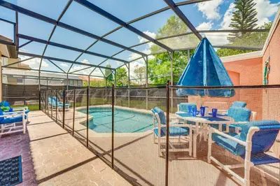 a patio with a table and chairs and a swimming pool at 7 Mi to Disney Kissimmee Poolside Paradise! in Kissimmee