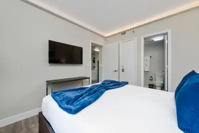 a bedroom with a white bed and a flat screen tv at 2 Suites at The Enclave Near Universal in Orlando