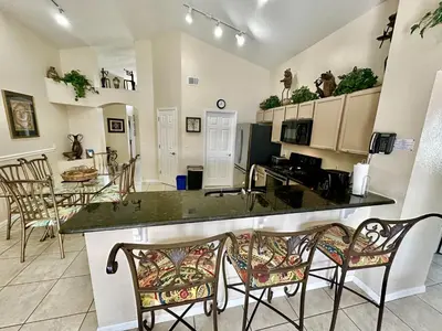 a kitchen and living room with a counter and chairs at EP1015SEL - 4 bedrooms - 8 guests pool home on a lake in Kissimmee