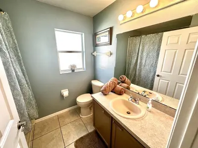 a bathroom with a sink and a toilet and a mirror at EP1015SEL - 4 bedrooms - 8 guests pool home on a lake in Kissimmee