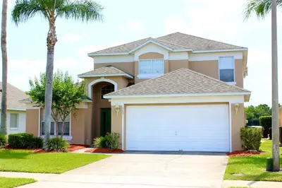 a house with a garage in a yard with palm trees at 637- Huge 5 Bed Villa with Amazing Water Views and Own Private Pool and Spa in Kissimmee