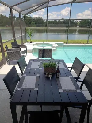 a wooden table with chairs and a swimming pool at 637- Huge 5 Bed Villa with Amazing Water Views and Own Private Pool and Spa in Kissimmee