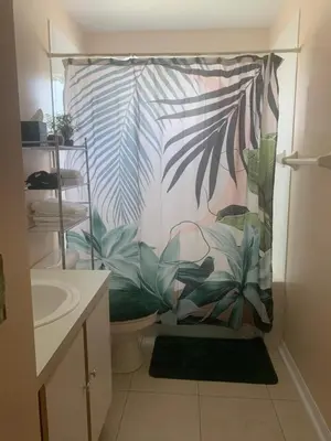 a bathroom with a shower curtain with plants at Spacious Condo Close to Disney Attractions in Kissimmee