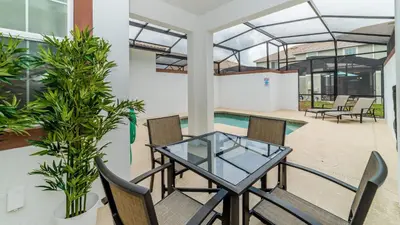 a patio with a glass table and chairs and a pool at Sea Haven in Orlando