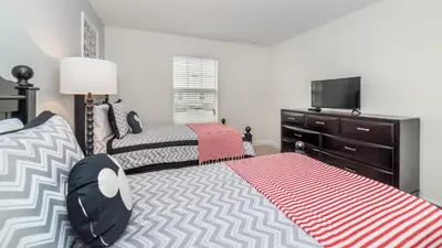 a bedroom with two beds and a tv and a dresser at Sea Haven in Orlando