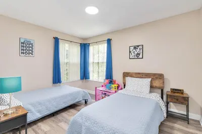 a bedroom with two beds and a window with blue curtains at Dream Condo in Kissimmee