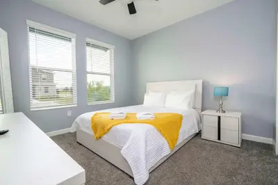 a bedroom with a bed with a yellow blanket on it at Luxury 6BR Resort Home - Pool, Hot Tub & BBQ - Near Disney! in Kissimmee