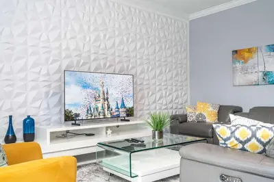 a living room with a flat screen tv on a wall at Luxury 6BR Resort Home - Pool, Hot Tub & BBQ - Near Disney! in Kissimmee