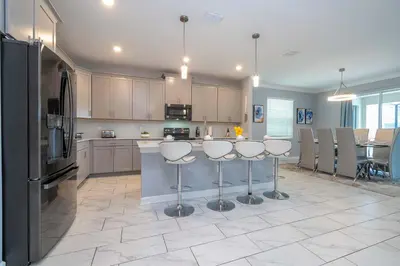 a kitchen with a counter with bar stools in it at Luxury 6BR Resort Home - Pool, Hot Tub & BBQ - Near Disney! in Kissimmee