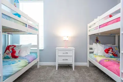 a bedroom with two bunk beds and a side table at Luxury 6BR Resort Home - Pool, Hot Tub & BBQ - Near Disney! in Kissimmee