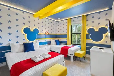 two beds in a room with mickey mouse wallpaper at 3240 Townhouse Perfect for Disney Visits 3BD in Kissimmee