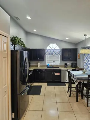 a kitchen with black cabinets and a table and a refrigerator at Minnie Heaven in Kissimmee