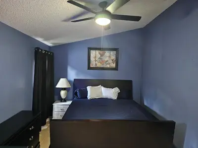 a blue bedroom with a bed with a ceiling fan at Mufasa's Pride in Kissimmee