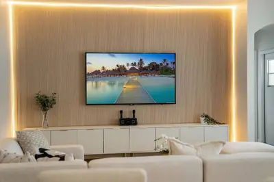 a living room with a flat screen tv on a wall at EPIC Theme 9D 360 Rotating Virtual Reality Machine 4 mi to Disney in Kissimmee