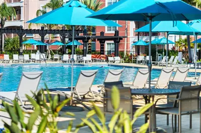 a group of chairs and umbrellas next to a swimming pool at Vista Cay at Epic Universe - Luxury 4 bedroom Condo in Orlando